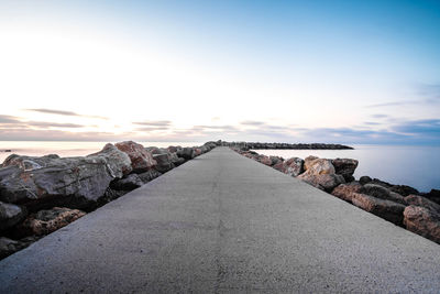 Rocks by road against sky during sunset