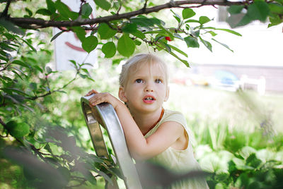 Portrait of little blondie girl in apple garden 