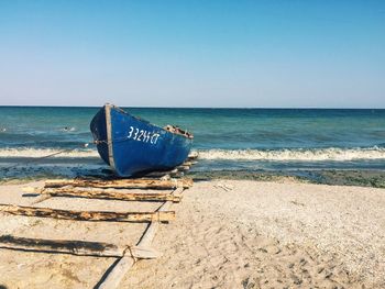 Deck chairs on beach against clear blue sky