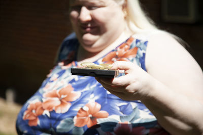 Smiling woman holding gift box standing outdoors