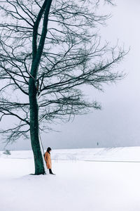 Woman on snow covered field against sky