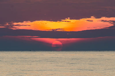 Scenic view of sea against dramatic sky during sunset