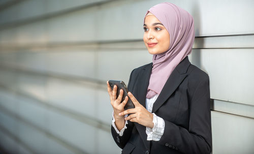 Portrait of a smiling young woman using mobile phone