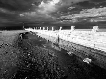 Wall with water against cloudy sky