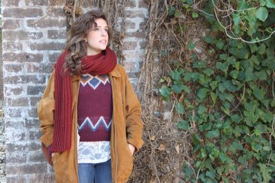 Full length of a smiling young woman standing against brick wall