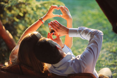 Rear view of couple photographing while sitting on chair