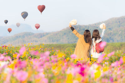 Rear view of women on field with flowers in background