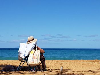 Rear view of man standing on beach against clear sky