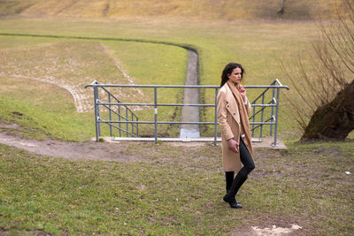 Full length portrait of woman standing on railing