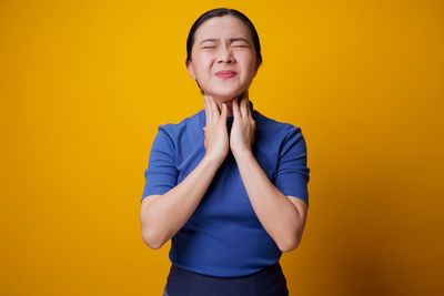 Portrait of beautiful young woman against yellow background