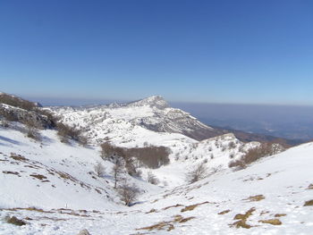 Scenic view of snowcapped mountains against clear blue sky