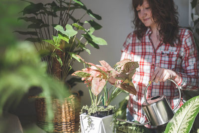 Portrait of young woman holding potted plant