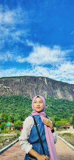 Portrait of young woman standing against sky