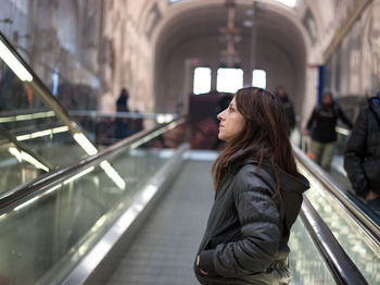 Side view of woman standing on moving walkway at milano centrale railway station