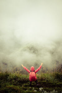 Rear view of woman in field against sky