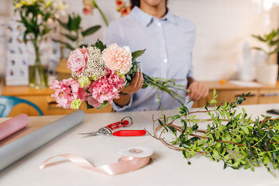 Midsection of woman holding flowers on table