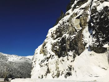 Low angle view of snowcapped mountains against clear sky