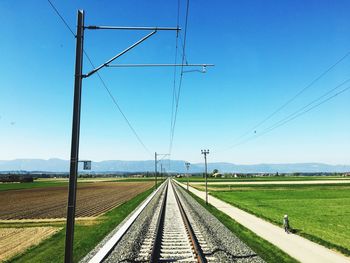 Railroad track amidst field against clear sky