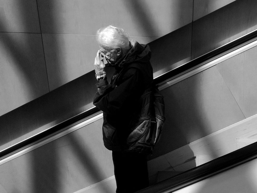 indoors, railing, low angle view, full length, steps, architecture, lifestyles, casual clothing, built structure, staircase, steps and staircases, standing, men, escalator, rear view, leisure activity, wall - building feature, three quarter length