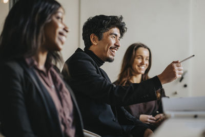 Happy male entrepreneur pointing during business meeting with female colleagues at office