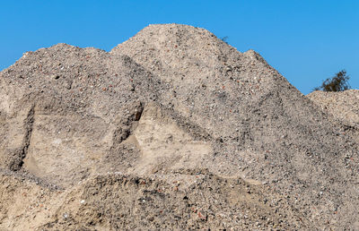 Low angle view of rocks against clear blue sky