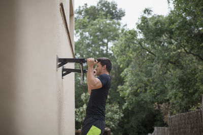 Side view of young man exercising on wall