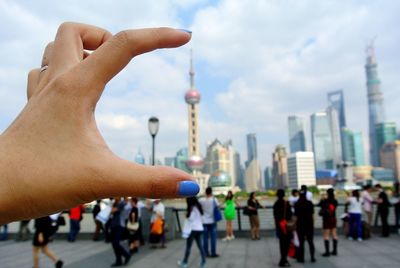 Optical illusion of person holding oriental pearl tower in city