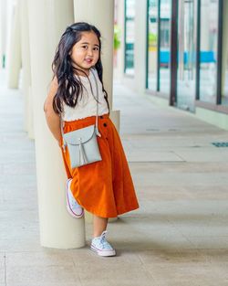 Portrait of cute girl leaning on column in corridor