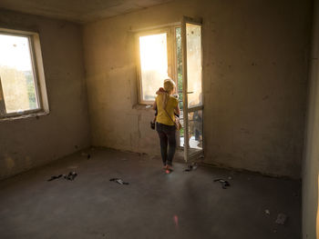 Rear view of woman carrying son at entrance of old empty room