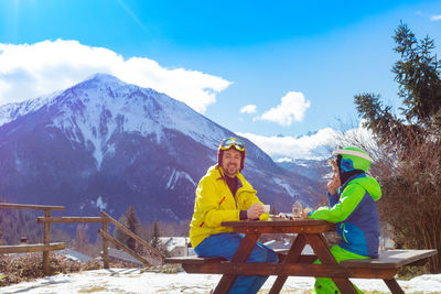 Rear view of people on snowcapped mountain against sky