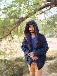 Portrait of beautiful young man standing against trees