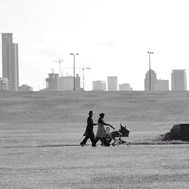 building exterior, men, architecture, built structure, lifestyles, city, leisure activity, clear sky, copy space, person, sitting, togetherness, sky, bonding, city life, urban skyline, cityscape