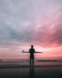 Rear view of silhouette man standing against sky during sunset