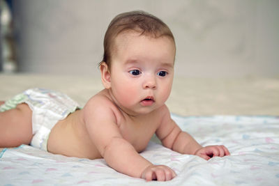 Baby girl lying on the bed in a diaper