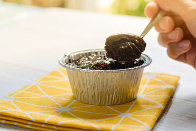 Eatting dark chocolate cake with chocolate chip topping in foil cup.