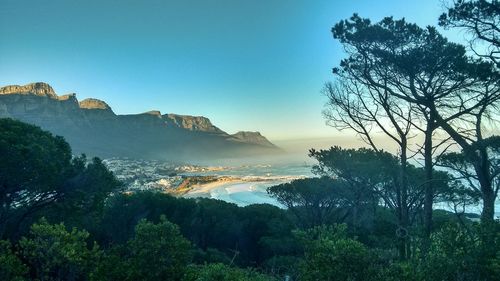 Scenic view of beach by mountains against sky during sunrise