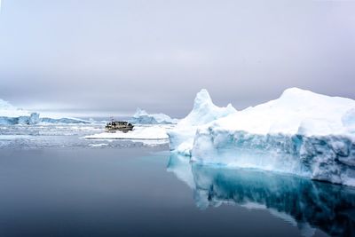 Glacier on frozen lake against sky