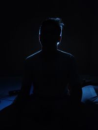 Rear view of man sitting in the dark