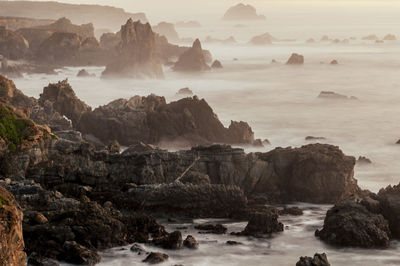 Rocks on sea shore against sky