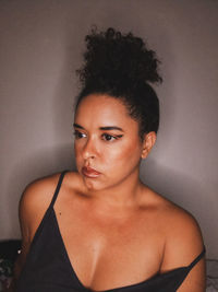 Portrait of young woman standing against wall at home