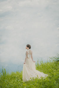 Woman with arms raised on field against sky