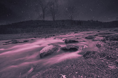 Scenic view of snow covered field against sky at night