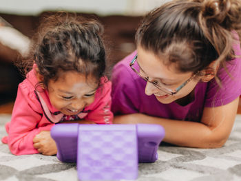 Mother and mixed race daughter at home having fun using a learning tablet computer 