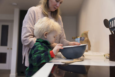 Mother and son by food on table at home