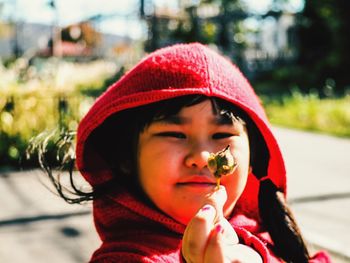 Close-up of girl holding bud during sunny day