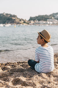 Side view of boy sitting on beach