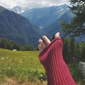 Midsection of woman with arms raised on mountain