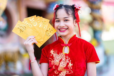 Portrait of smiling girl holding envelopes outdoors