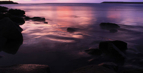 Rocks on beach against sky during sunset