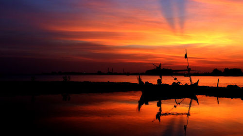 Silhouette boats in sea against orange sky